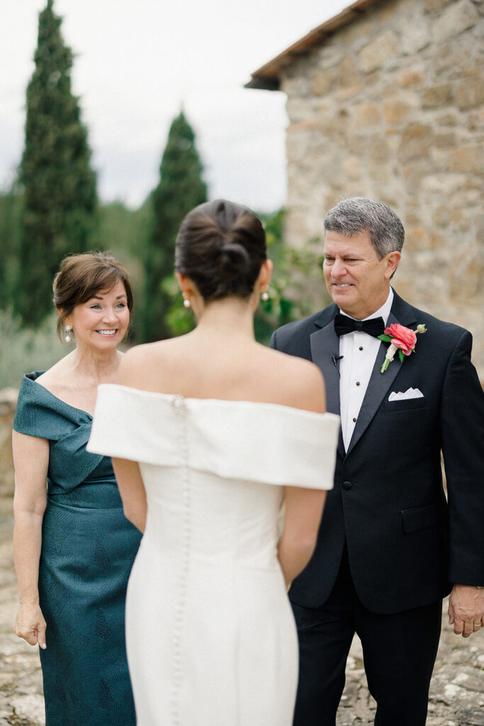 Campbell walking down the aisle during her wedding ceremony at Villa Ardore in Chianti, Tuscany, surrounded by vineyards and close family members in an intimate outdoor Italian wedding setting.