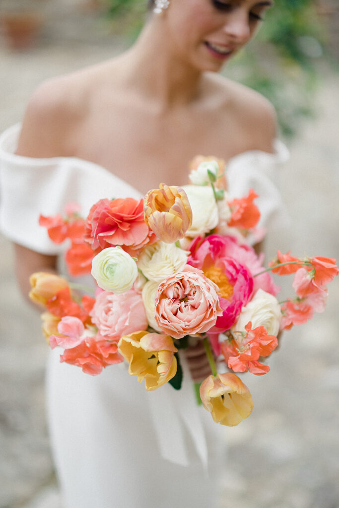Campbell standing outside at Villa Ardore in Chianti, Tuscany, in her wedding dress holding her bouquet, with vineyards and the Italian countryside surrounding her during her destination wedding.
