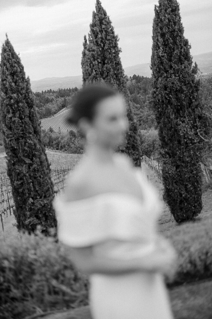 Campbell standing outside at Villa Ardore in Chianti, Tuscany, in her wedding dress holding her bouquet, with vineyards and the Italian countryside surrounding her during her destination wedding.