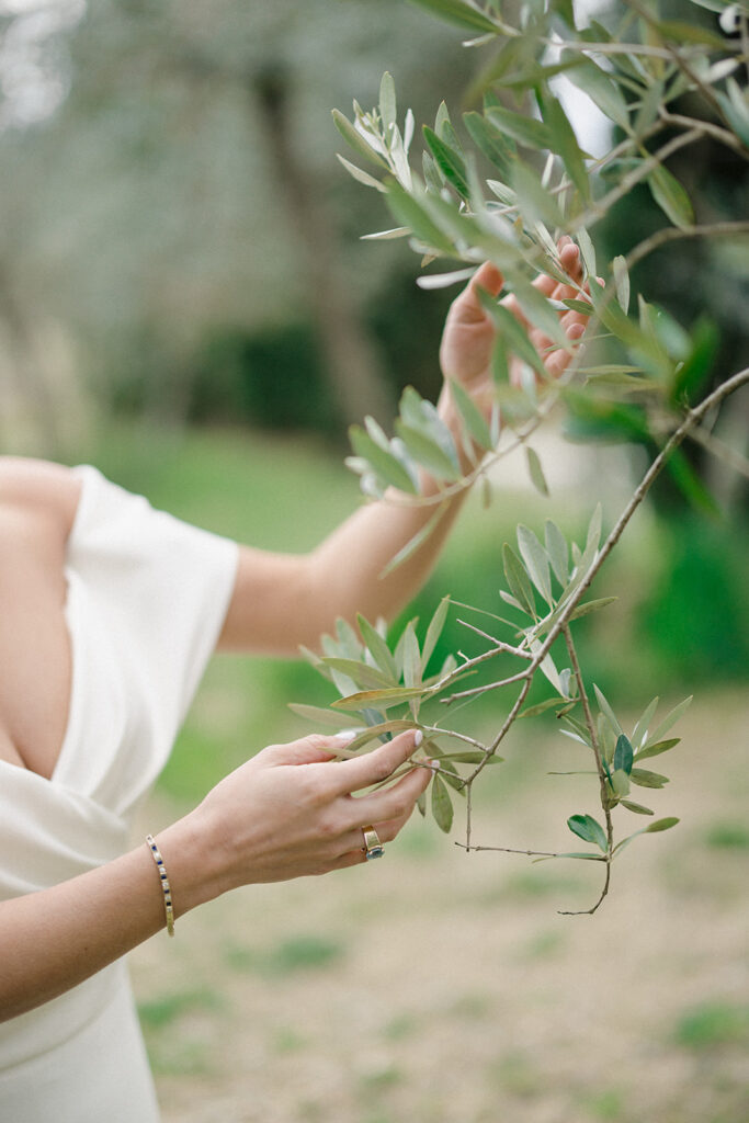 Campbell standing outside at Villa Ardore in Chianti, Tuscany, in her wedding dress holding her bouquet, with vineyards and the Italian countryside surrounding her during her destination wedding.