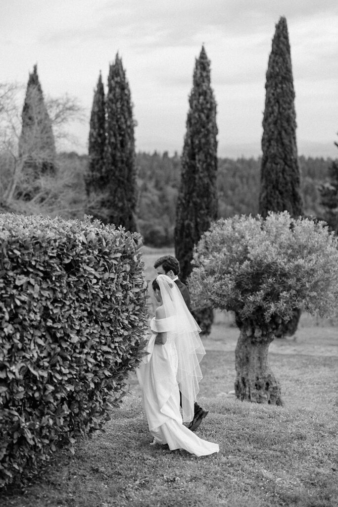 Campbell standing outside at Villa Ardore in Chianti, Tuscany, in her wedding dress holding her bouquet, with vineyards and the Italian countryside surrounding her during her destination wedding.