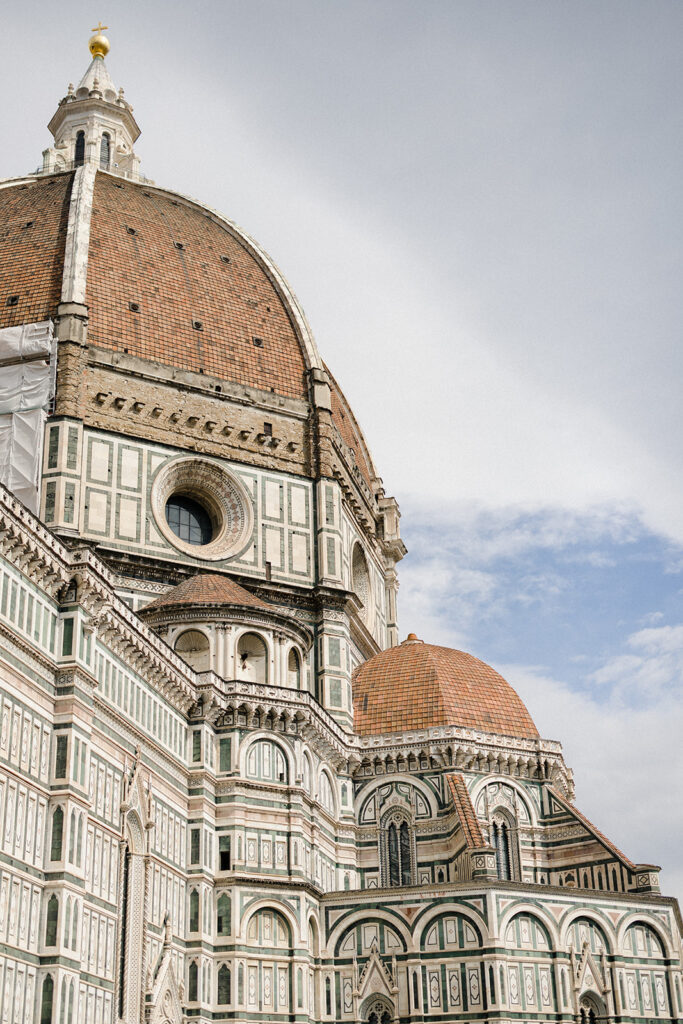 Campbell and Stuart during their engagement session in Florence, Italy, walking through historic cobblestone streets surrounded by classic Renaissance architecture at golden hour before their Tuscany wedding celebration.