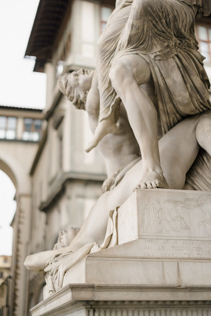 Campbell and Stuart during their engagement session in Florence, Italy, walking through historic cobblestone streets surrounded by classic Renaissance architecture at golden hour before their Tuscany wedding celebration.
