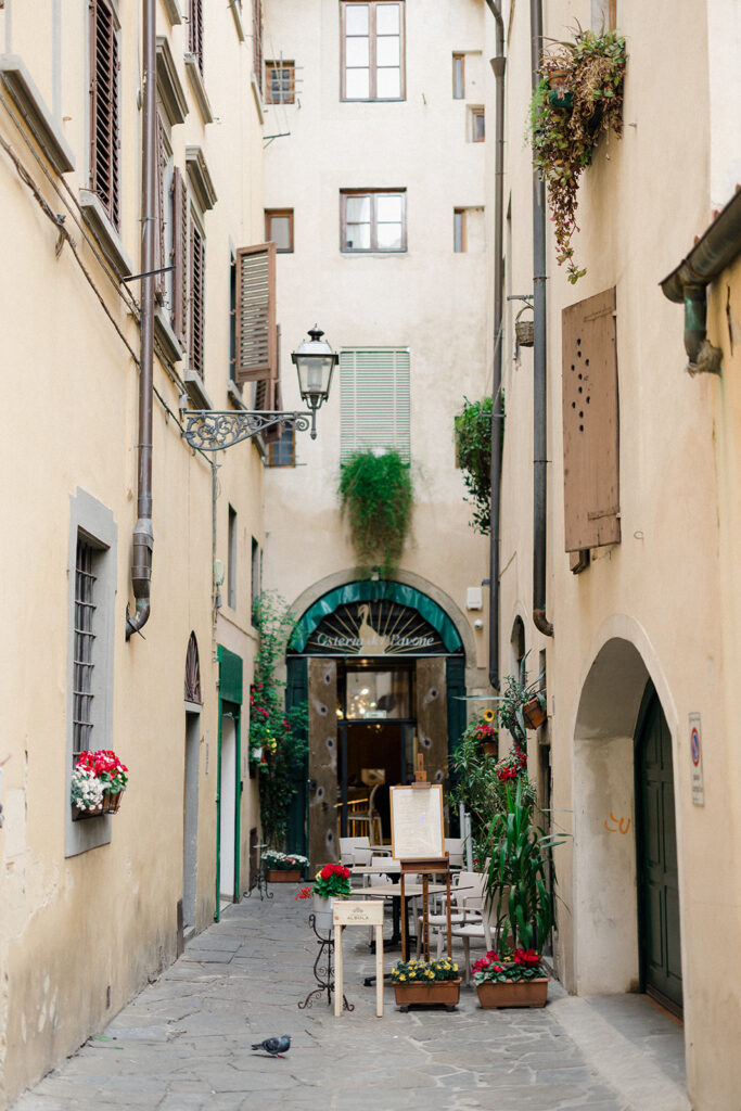 Campbell and Stuart during their engagement session in Florence, Italy, walking through historic cobblestone streets surrounded by classic Renaissance architecture at golden hour before their Tuscany wedding celebration.