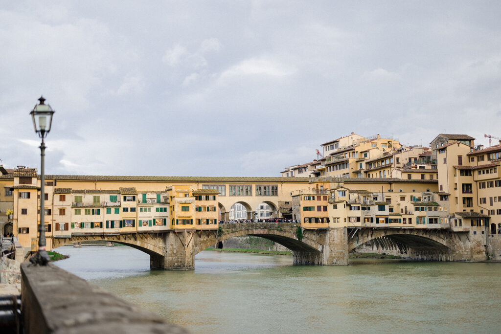 Campbell and Stuart during their engagement session in Florence, Italy, walking through historic cobblestone streets surrounded by classic Renaissance architecture at golden hour before their Tuscany wedding celebration.