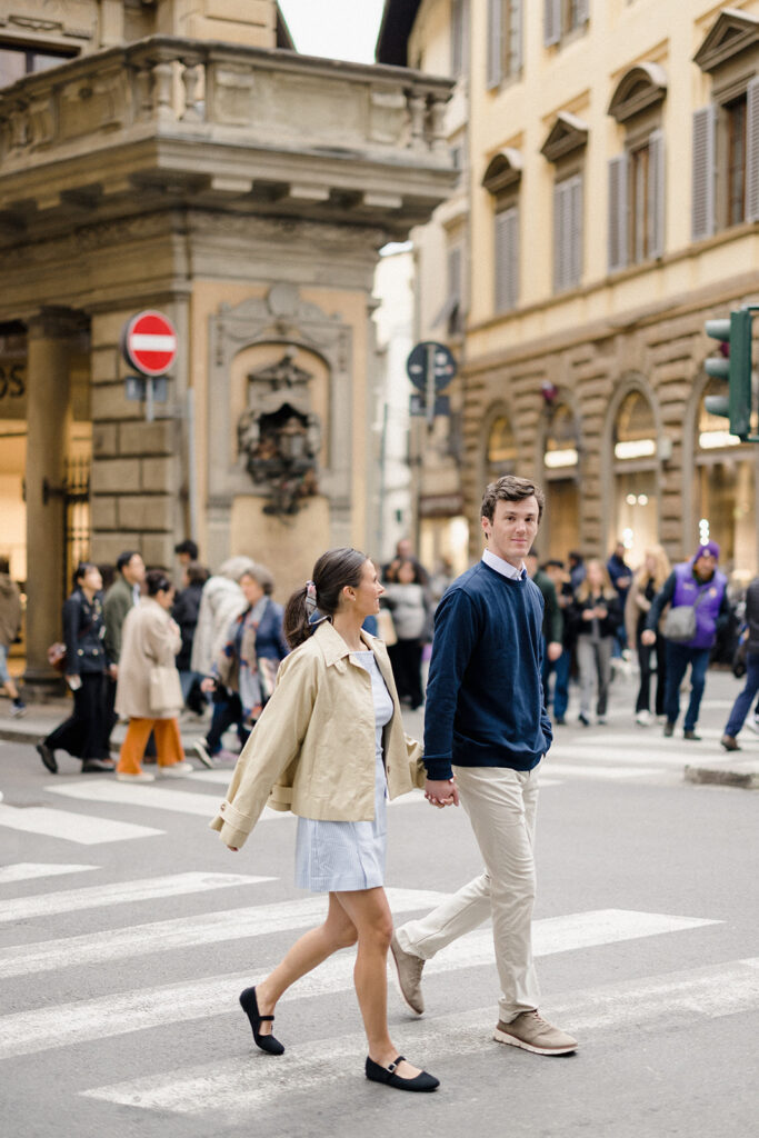 Campbell and Stuart during their engagement session in Florence, Italy, walking through historic cobblestone streets surrounded by classic Renaissance architecture at golden hour before their Tuscany wedding celebration.