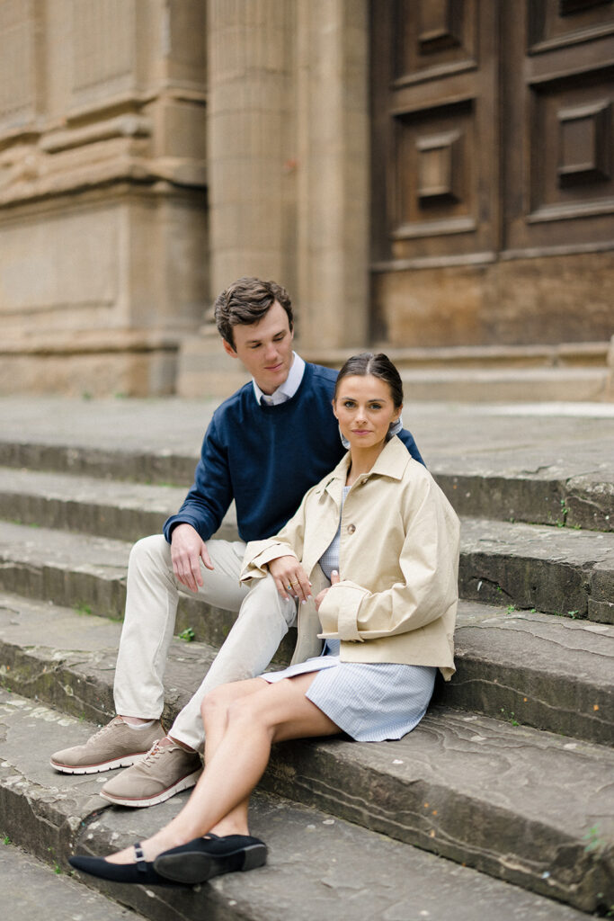 Campbell and Stuart during their engagement session in Florence, Italy, walking through historic cobblestone streets surrounded by classic Renaissance architecture at golden hour before their Tuscany wedding celebration.