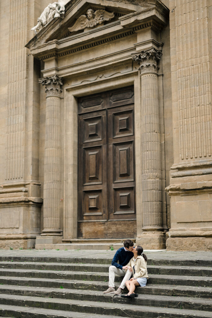 Campbell and Stuart during their engagement session in Florence, Italy, walking through historic cobblestone streets surrounded by classic Renaissance architecture at golden hour before their Tuscany wedding celebration.