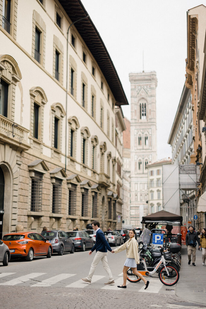 Campbell and Stuart during their engagement session in Florence, Italy, walking through historic cobblestone streets surrounded by classic Renaissance architecture at golden hour before their Tuscany wedding celebration.