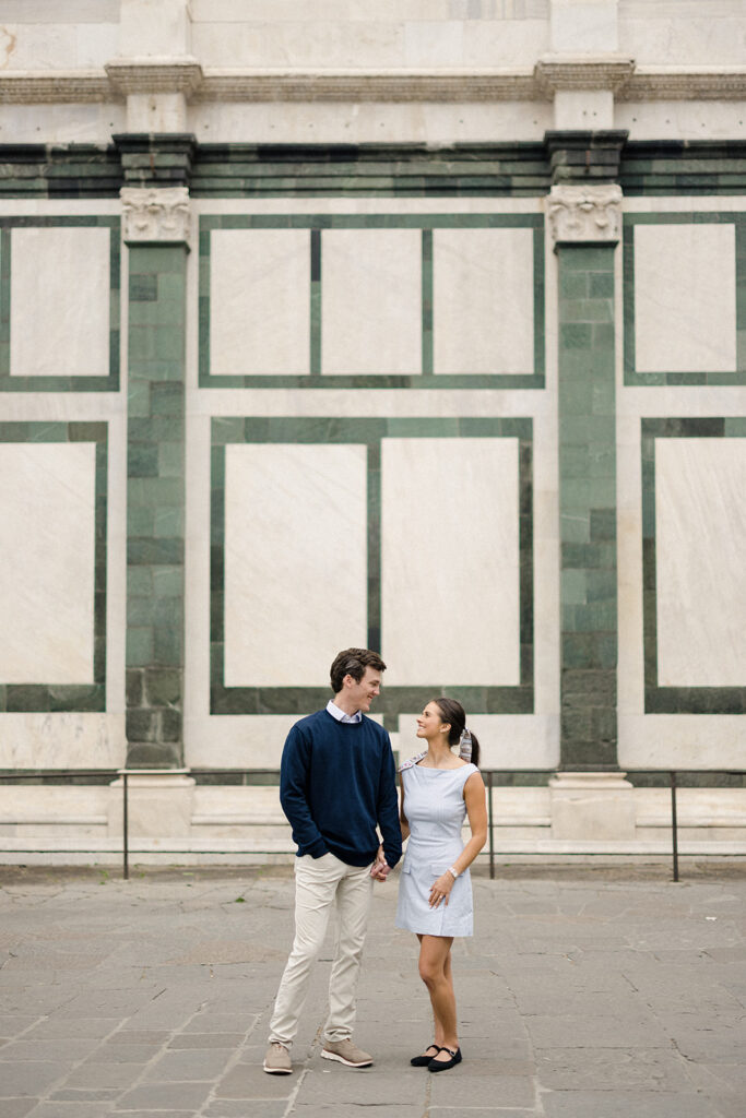 Campbell and Stuart during their engagement session in Florence, Italy, walking through historic cobblestone streets surrounded by classic Renaissance architecture at golden hour before their Tuscany wedding celebration.