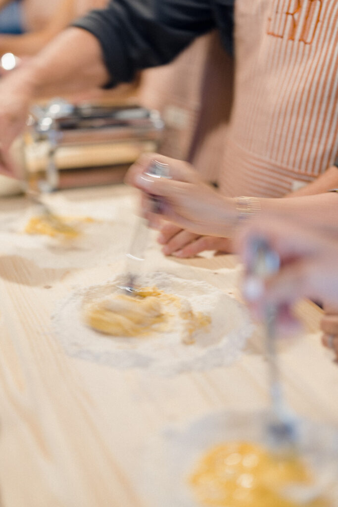 Campbell and Stuart participating in a hands-on cooking class in Italy, surrounded by family and shared laughter.
