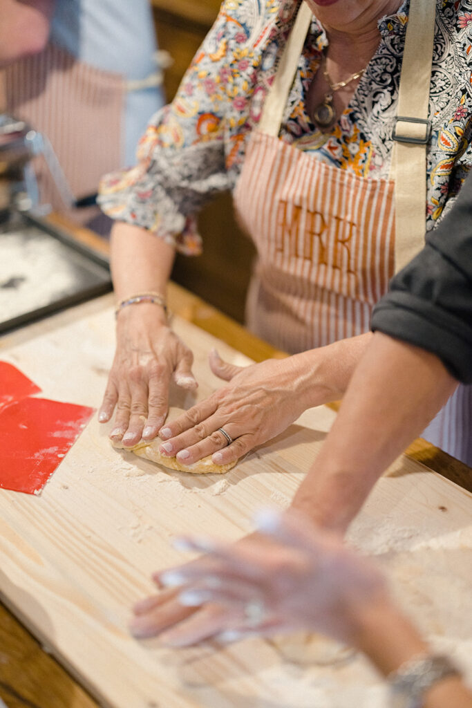 Campbell and Stuart participating in a hands-on cooking class in Italy, surrounded by family and shared laughter.