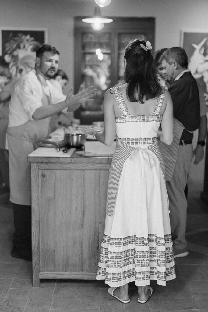 Campbell and Stuart participating in a hands-on cooking class in Italy, surrounded by family and shared laughter.