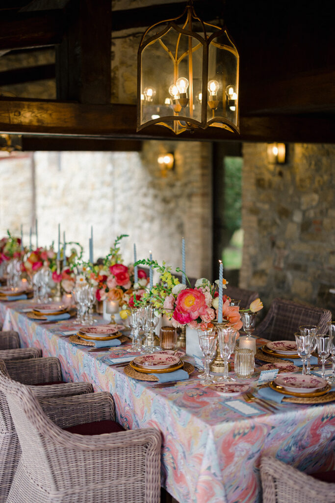 Candlelit wedding reception dinner at Villa Ardore in Chianti, Tuscany, with long tables, vibrant florals by Tuscany Flowers, and family gathered together overlooking the Tuscan hills at sunset.