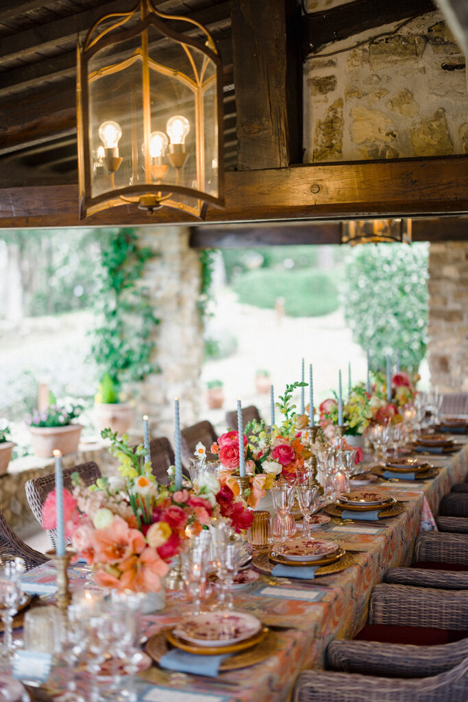 Candlelit wedding reception dinner at Villa Ardore in Chianti, Tuscany, with long tables, vibrant florals by Tuscany Flowers, and family gathered together overlooking the Tuscan hills at sunset.