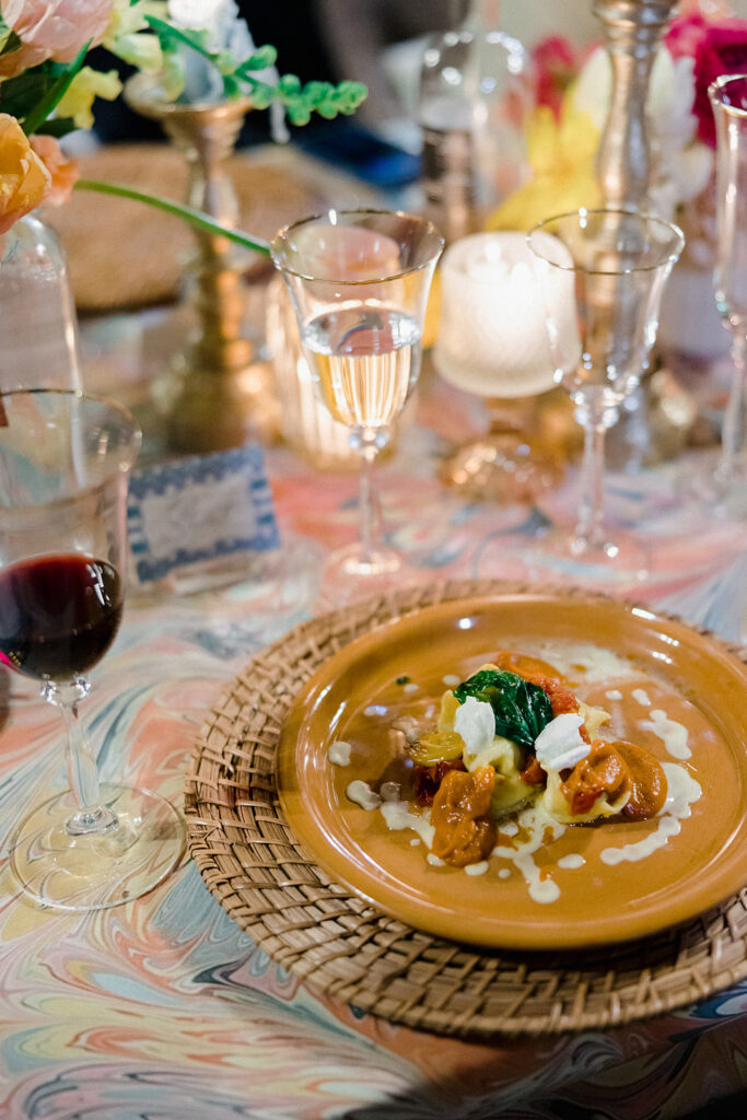 Candlelit wedding reception dinner at Villa Ardore in Chianti, Tuscany, with long tables, vibrant florals by Tuscany Flowers, and family gathered together overlooking the Tuscan hills at sunset.