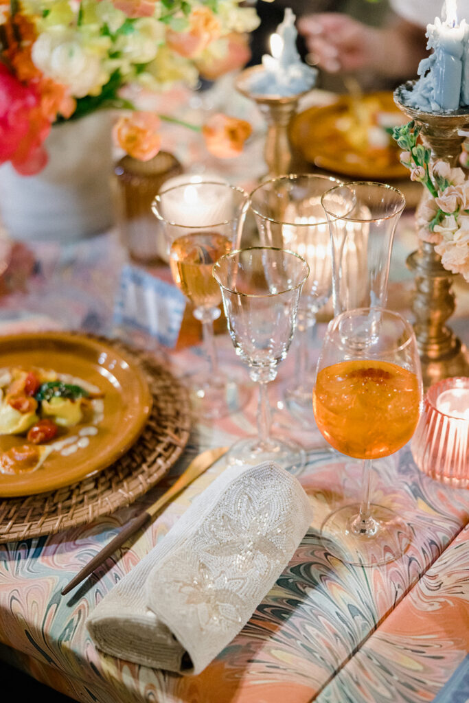 Candlelit wedding reception dinner at Villa Ardore in Chianti, Tuscany, with long tables, vibrant florals by Tuscany Flowers, and family gathered together overlooking the Tuscan hills at sunset.