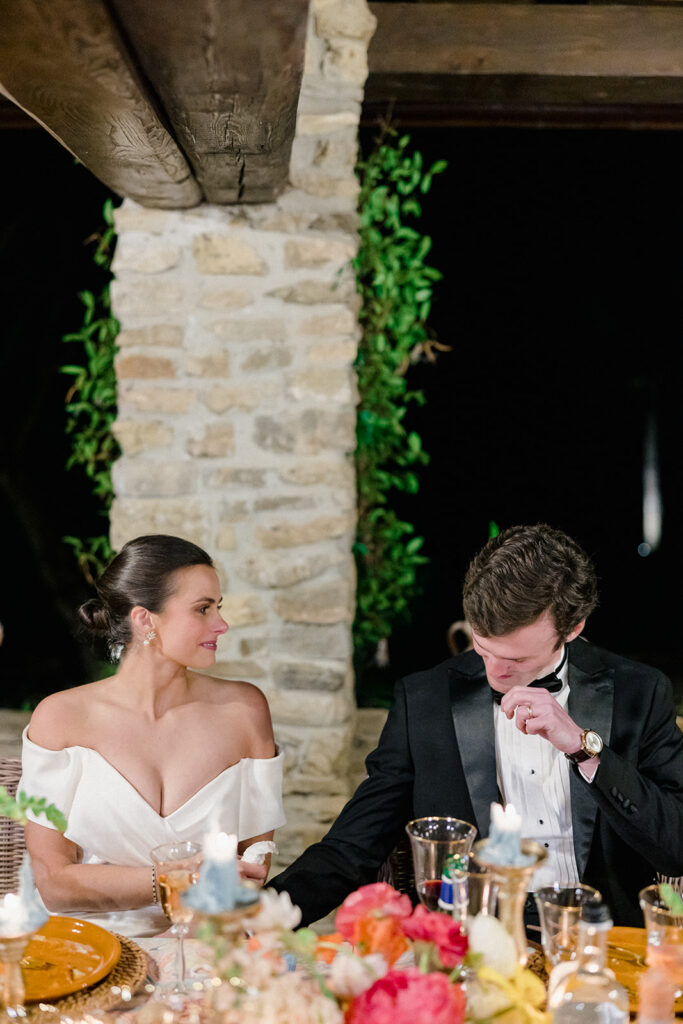 Candlelit wedding reception dinner at Villa Ardore in Chianti, Tuscany, with long tables, vibrant florals by Tuscany Flowers, and family gathered together overlooking the Tuscan hills at sunset.