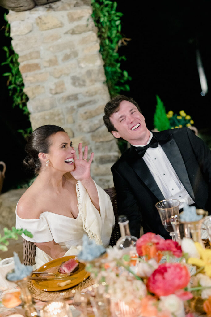 Candlelit wedding reception dinner at Villa Ardore in Chianti, Tuscany, with long tables, vibrant florals by Tuscany Flowers, and family gathered together overlooking the Tuscan hills at sunset.