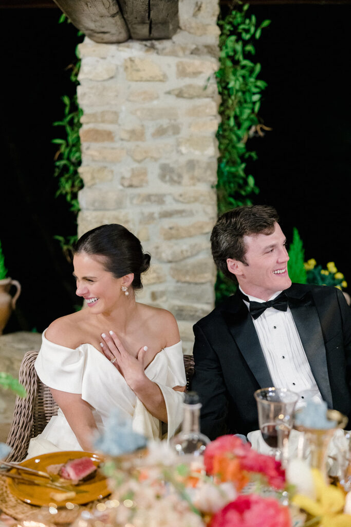 Candlelit wedding reception dinner at Villa Ardore in Chianti, Tuscany, with long tables, vibrant florals by Tuscany Flowers, and family gathered together overlooking the Tuscan hills at sunset.