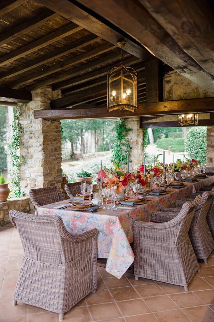 Candlelit wedding reception dinner at Villa Ardore in Chianti, Tuscany, with long tables, vibrant florals by Tuscany Flowers, and family gathered together overlooking the Tuscan hills at sunset.