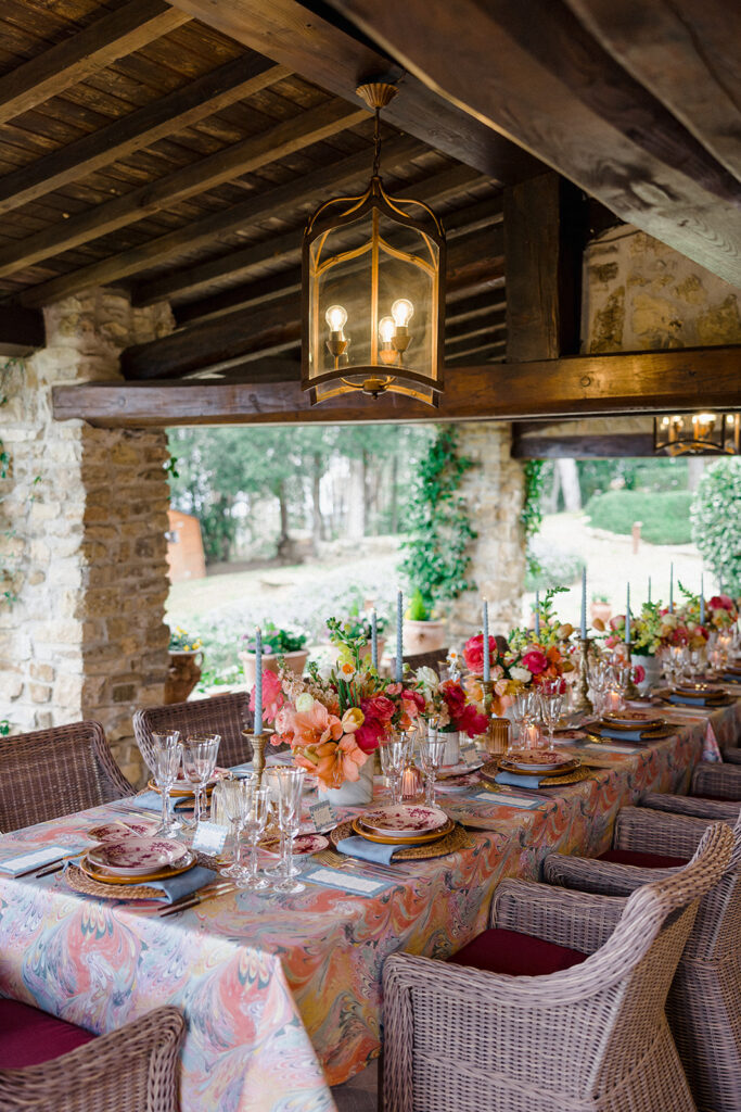 Candlelit wedding reception dinner at Villa Ardore in Chianti, Tuscany, with long tables, vibrant florals by Tuscany Flowers, and family gathered together overlooking the Tuscan hills at sunset.