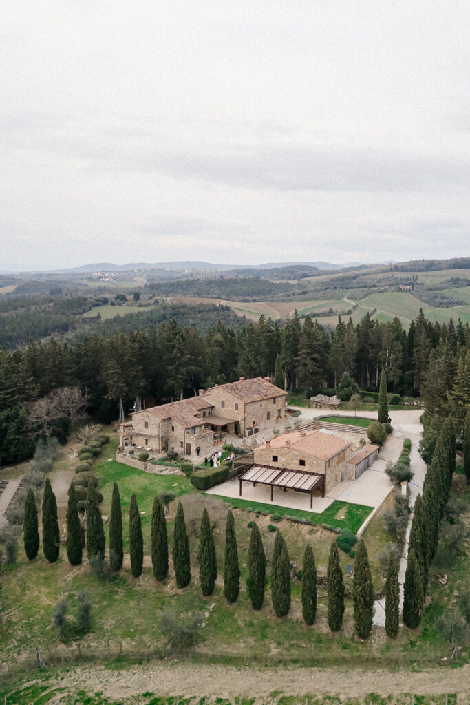 Campbell walking down the aisle during her wedding ceremony at Villa Ardore in Chianti, Tuscany, surrounded by vineyards and close family members in an intimate outdoor Italian wedding setting.